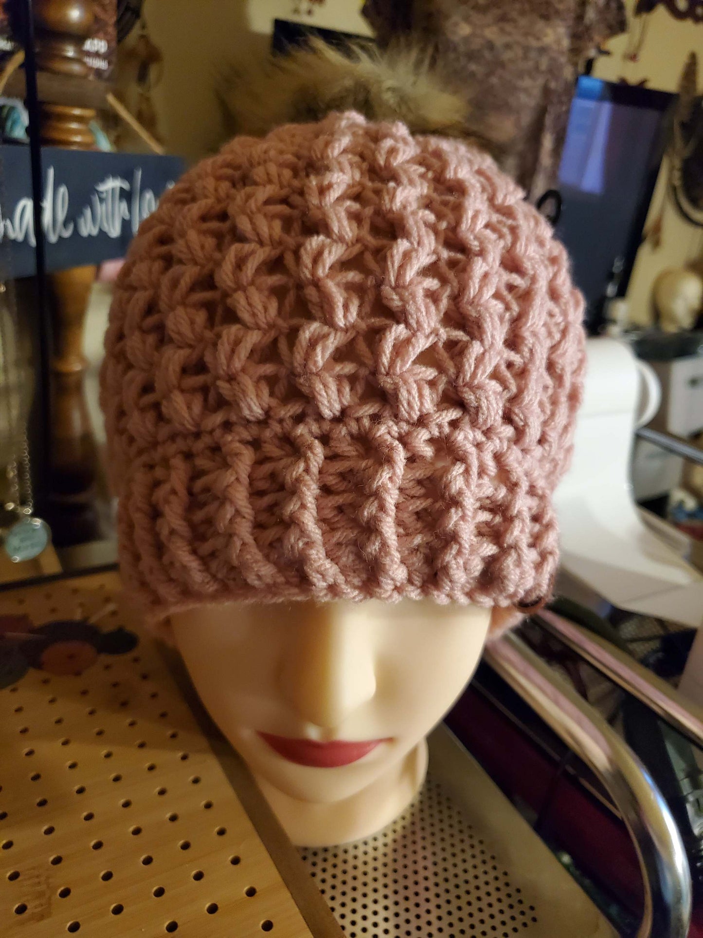 Mauve colored crocheted hat with pompom, fashion accessory.