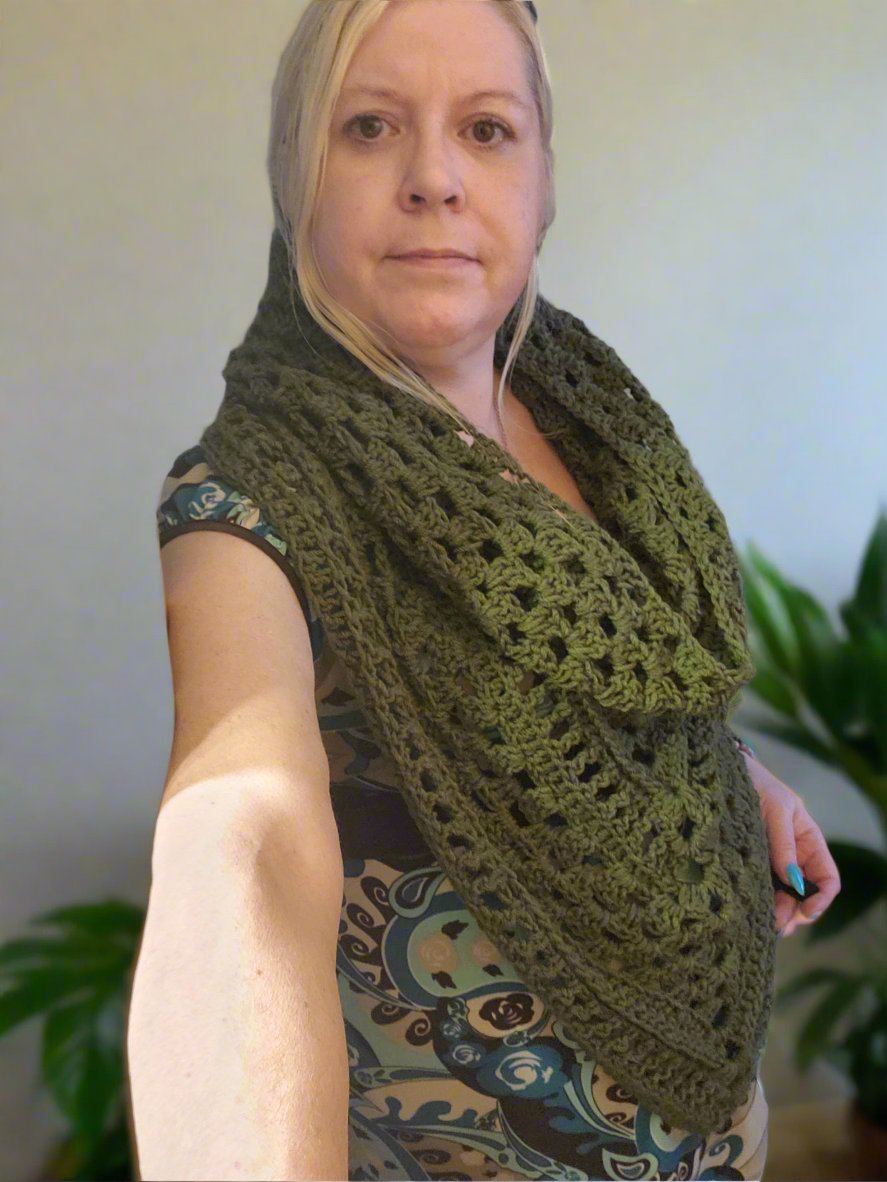Handmade crocheted boho hooded triangle scarf in olive green worn by a person.