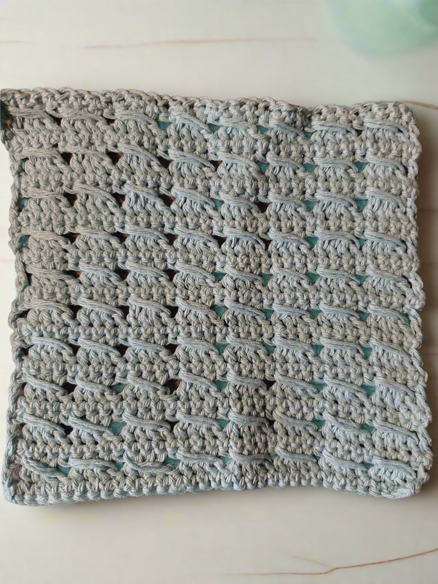Handmade textured aqua dishcloth with a unique pattern, ideal for washing dishes.