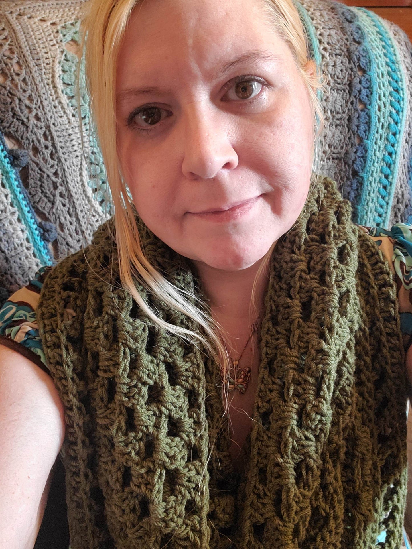 Handmade crocheted boho hooded triangle scarf in olive green worn by a model.