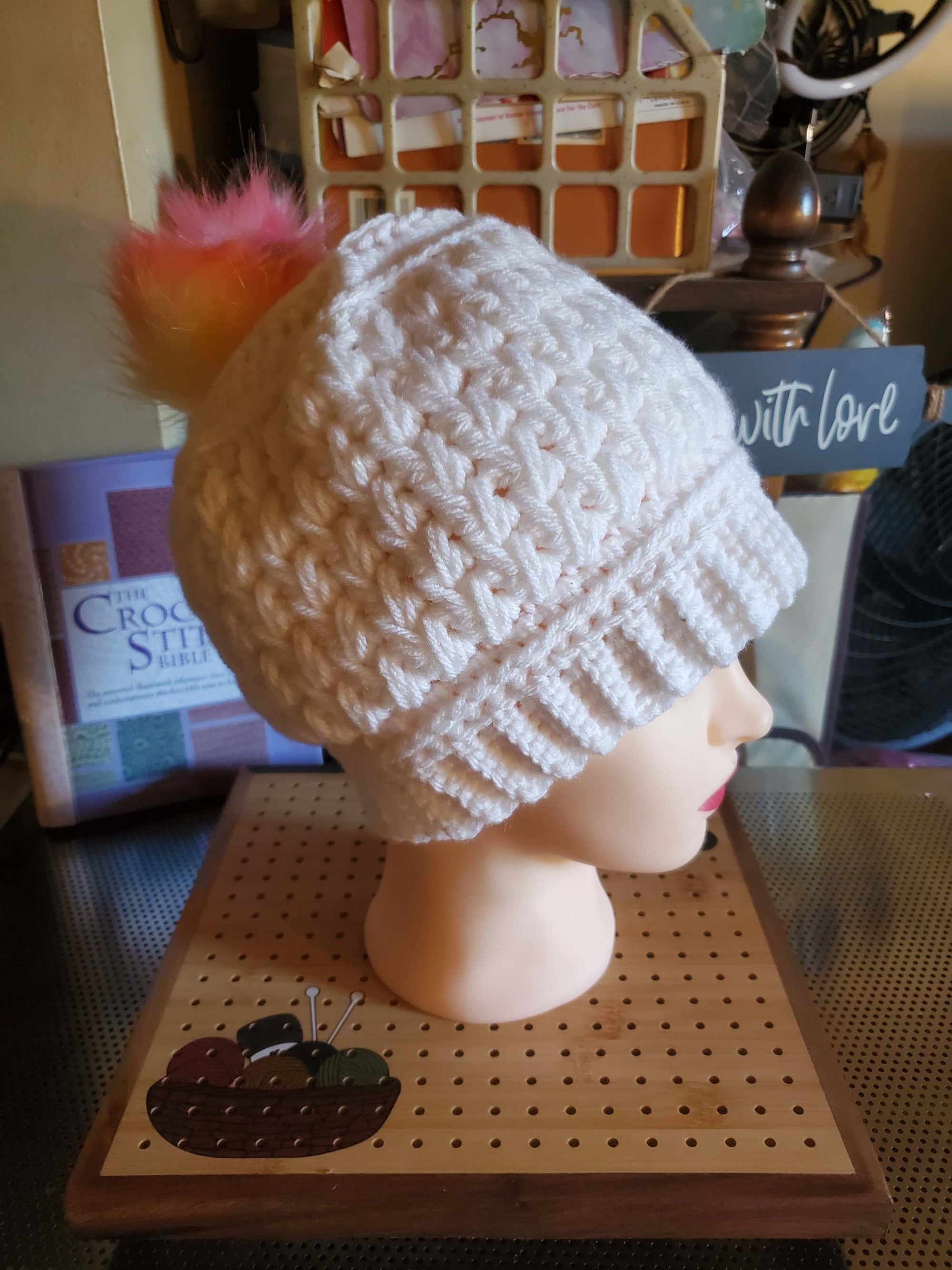 Handmade crocheted white feather stitch hat with rainbow pompom for women.