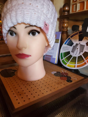 Handmade crocheted white feather stitch hat with rainbow pompom for women displayed on a mannequin.