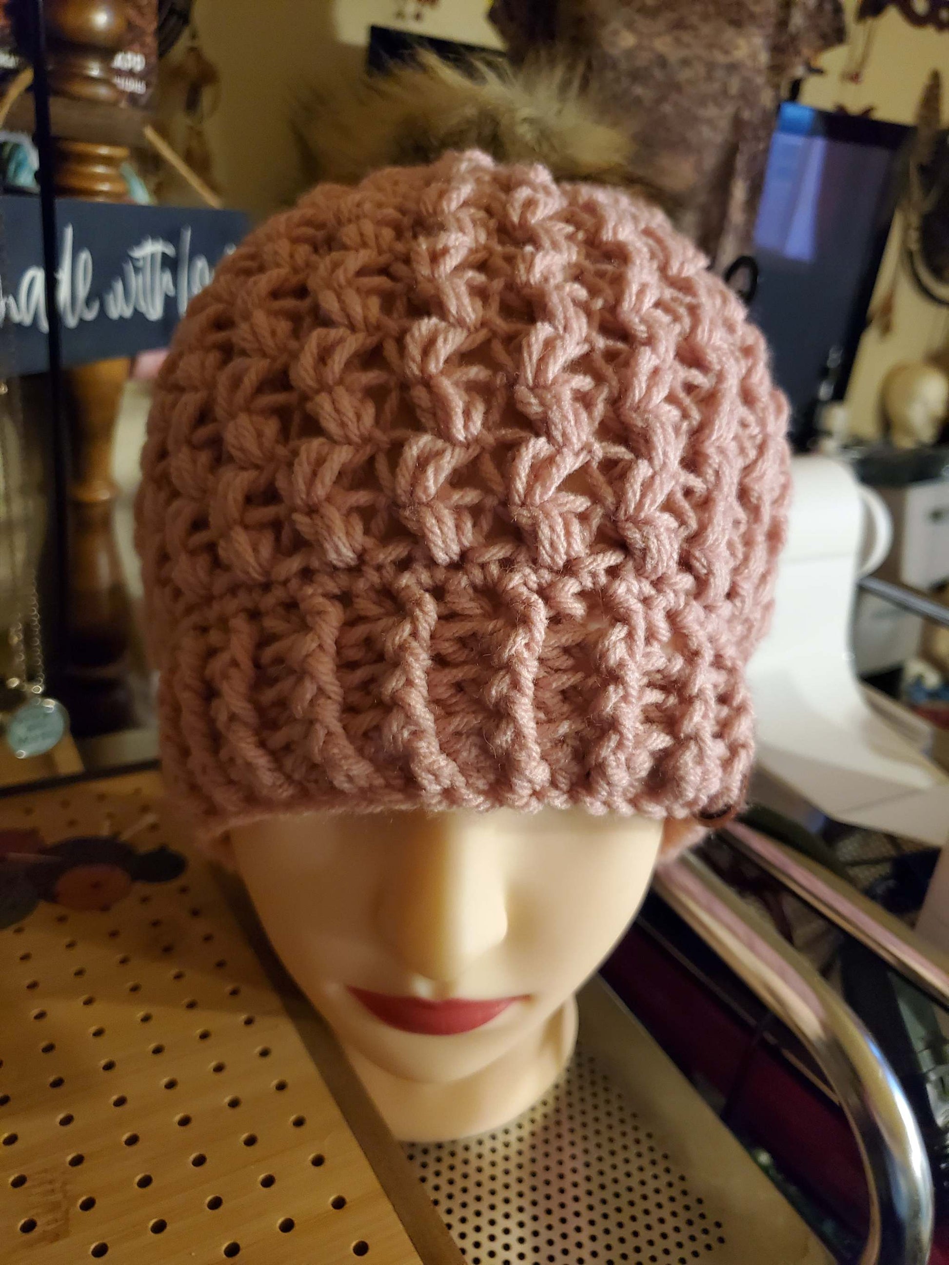 Mauve colored crocheted hat with pompom, fashion accessory.