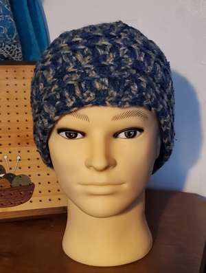 Blue and gray handmade crocheted men's beanie hat on mannequin head.