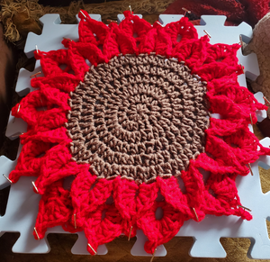 Crocheted red poinsettia placemat for Christmas decor.