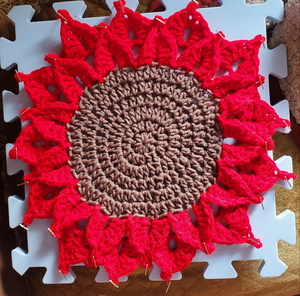 Crocheted red poinsettia placemat for Christmas table decor.