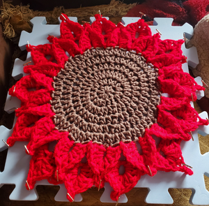 Crocheted Christmas red poinsettia placemat candleholder on table.