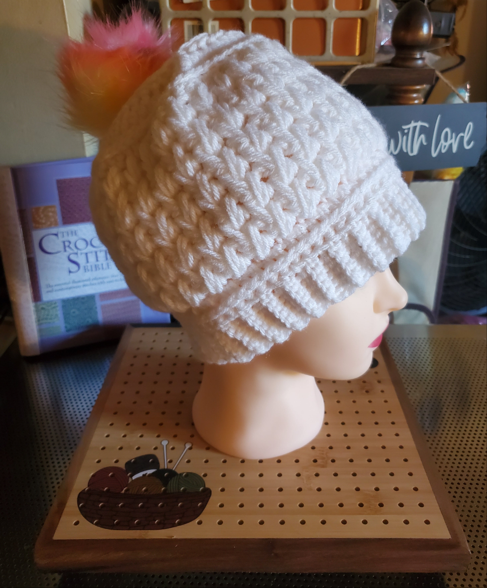 Handmade crocheted white feather stitch hat with rainbow pompom for women.