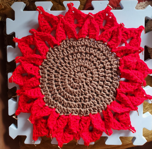 Crocheted red poinsettia placemat candleholder for Christmas decor.