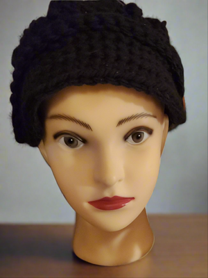 Black newsboy hat with crocheted buttons on mannequin head.