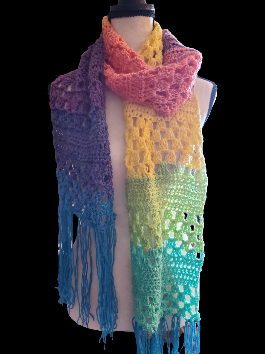Handmade granny stitch scarf with rainbow gradient and fringe, perfect for adding color and charm.