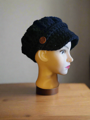 Black newsboy hat with crocheted buttons on a mannequin head.