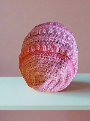 Beautifully crocheted soft pink hat on display.