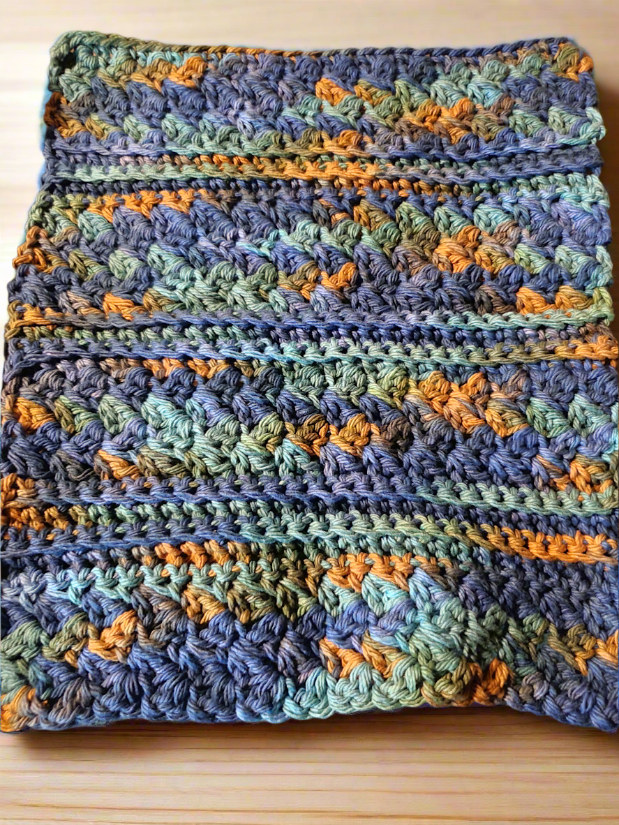 Set of 4 dishcloths in dark blue, green, and brown variegated pattern on wooden surface.
