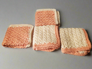 Set of four crocheted cream and tangerine dishcloths.