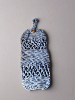 Handmade crocheted acrylic plastic bag holder hanging on wall, perfect for organizing.