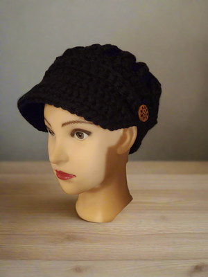 Black newsboy hat with crocheted buttons on display mannequin.