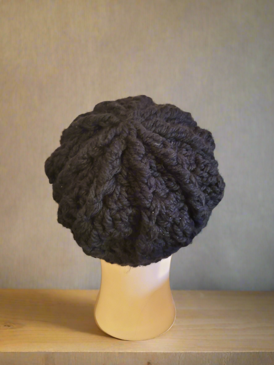 Black crocheted newsboy hat with buttons on mannequin.