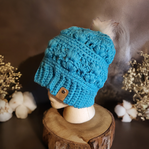 Handmade teal Amarie slouch hat with crochet details displayed on a mannequin.