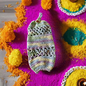 Handmade crocheted acrylic plastic bag holder on vibrant floral background.