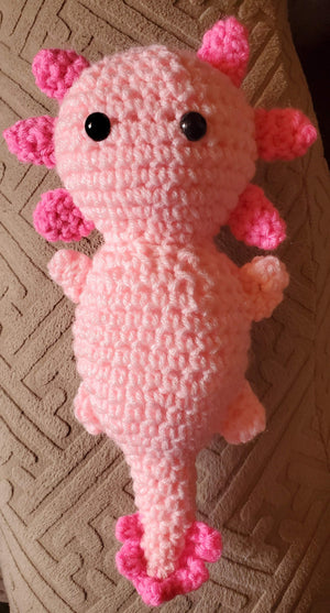 Adorable handmade crocheted stuffed axolotl toy with unique design and pink accents.