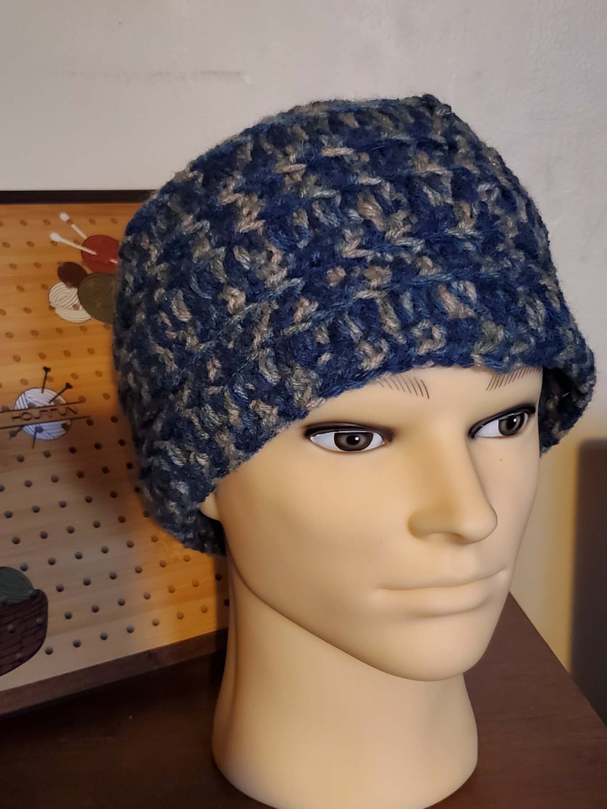 Blue and gray handmade crocheted men's beanie hat on display.