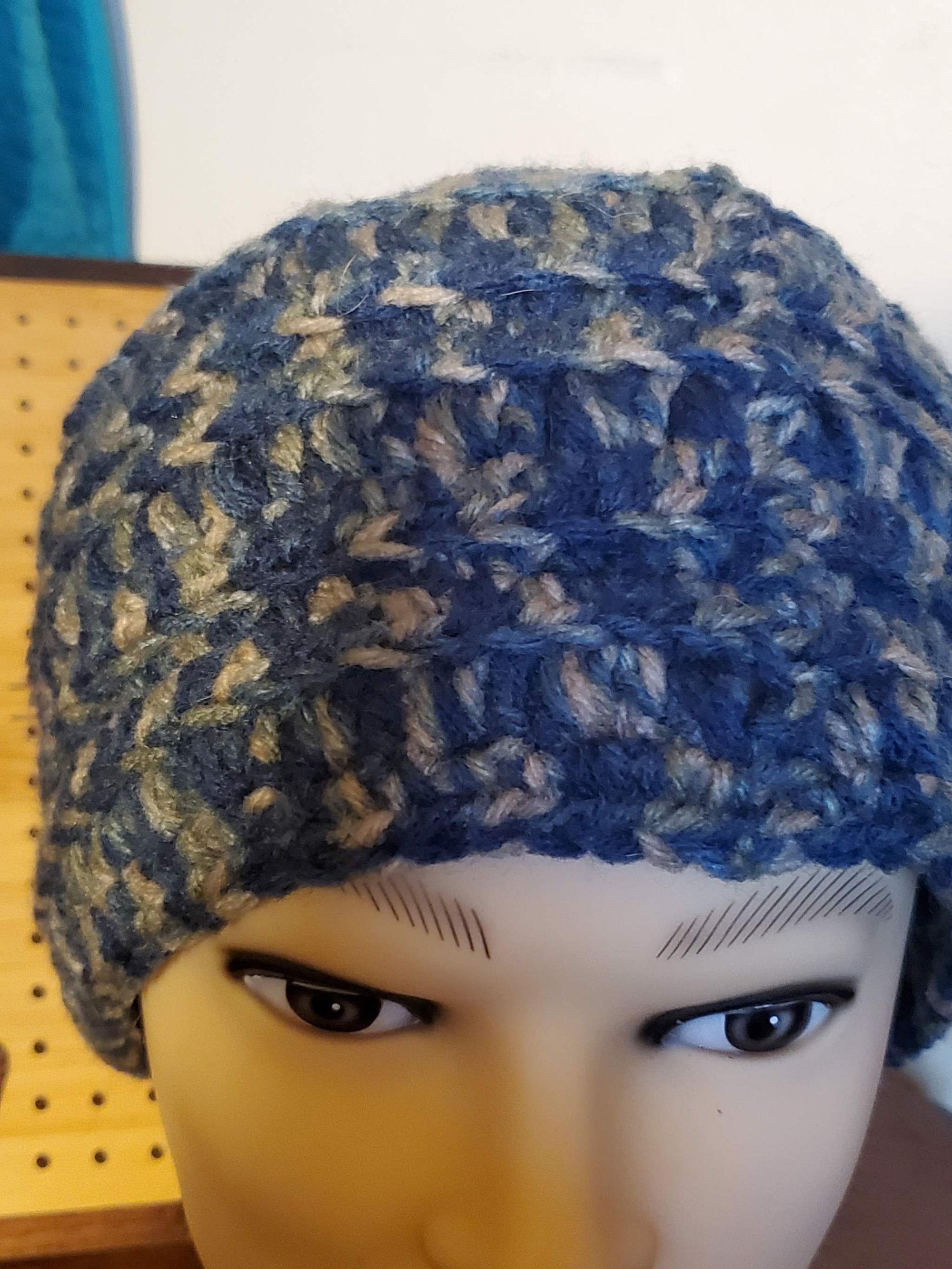 Blue and gray handmade crocheted men's beanie hat on display.