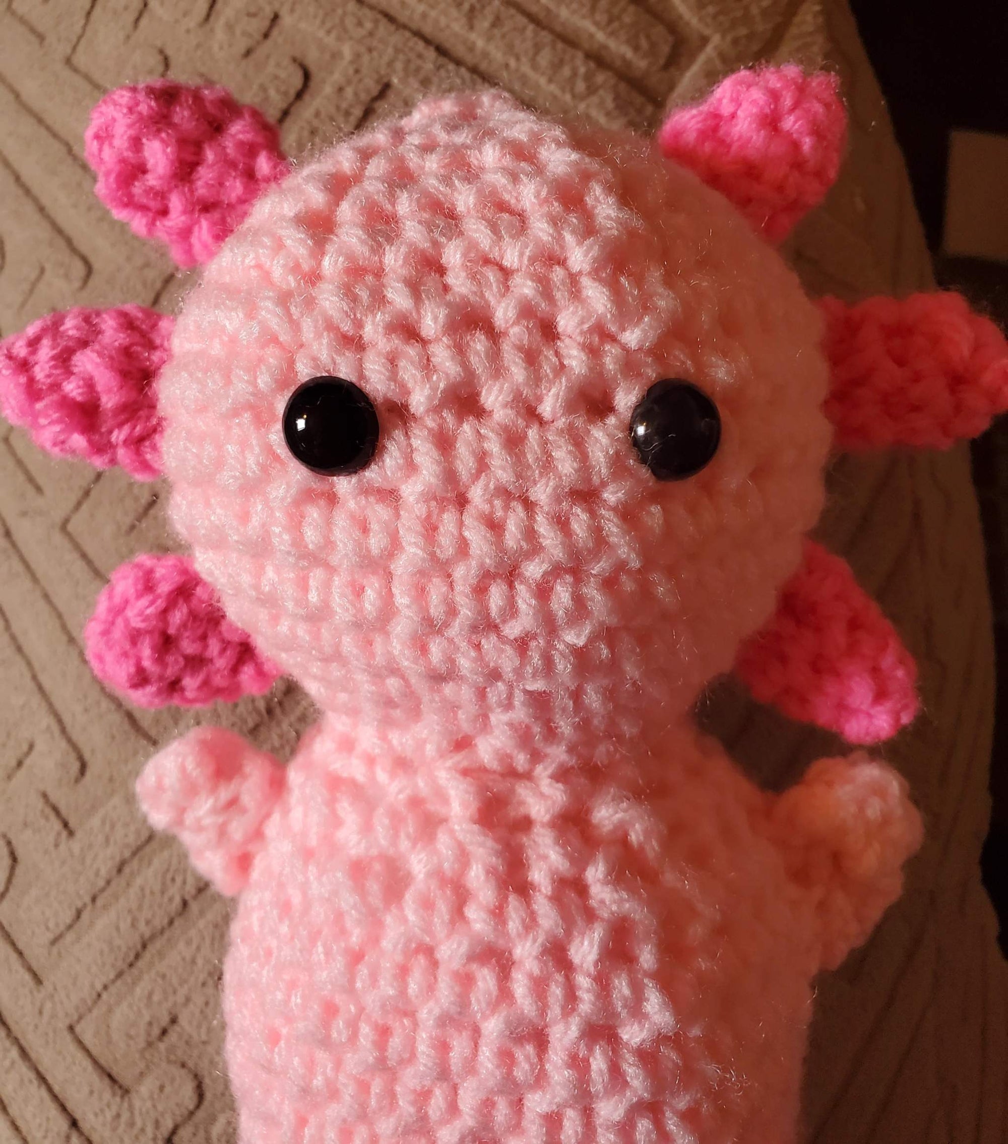 Adorable handmade crocheted stuffed axolotl toys in blue and pink.