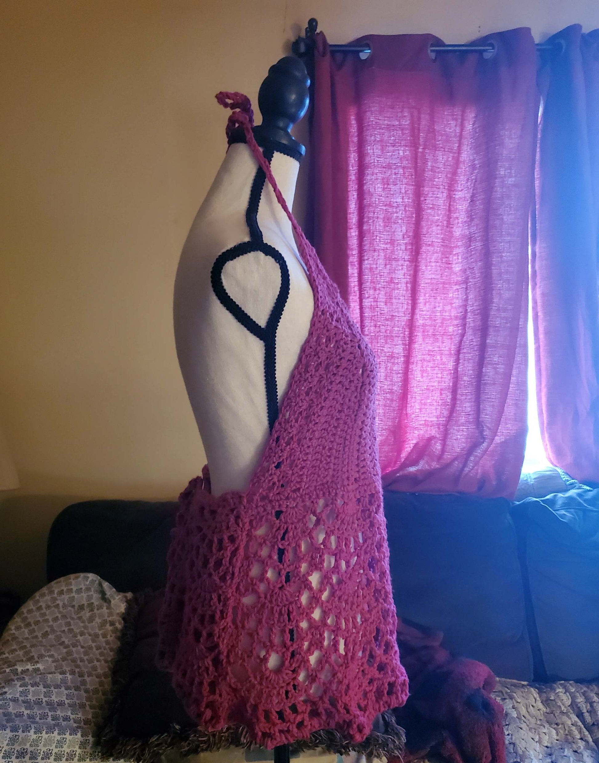 Pink lacy crochet halter top with scalloped hem and open back displayed on mannequin.