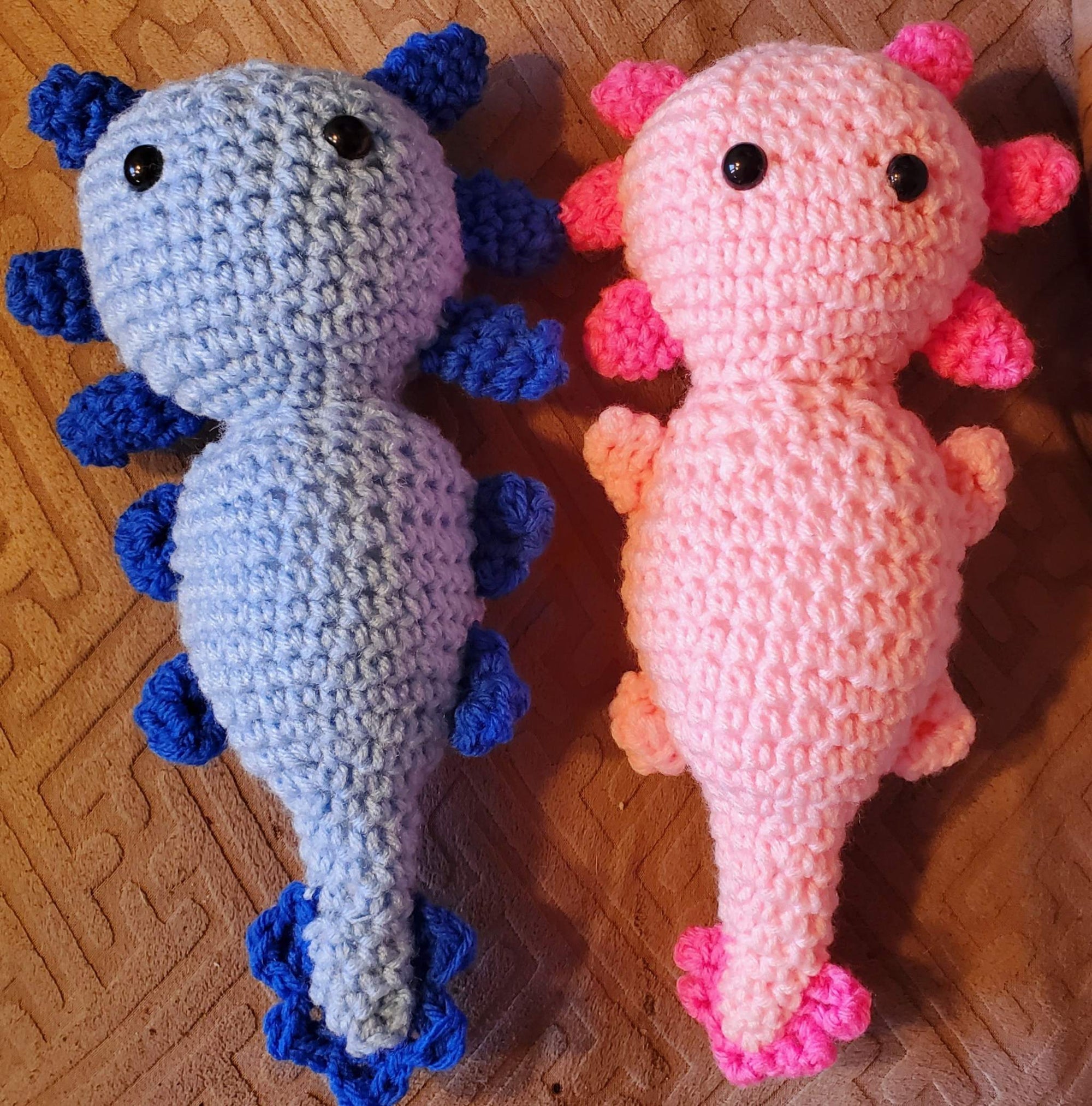 Adorable handmade crocheted stuffed axolotl toys in blue and pink.